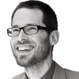 Joe smiling with glasses on looking off into distance